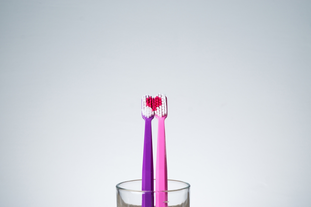 duas escovas de dente rosa e roxa em um copo