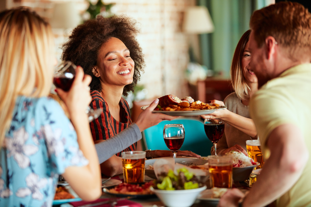 um grupo de pessoas sentadas ao redor de uma mesa com comidas e bebidas