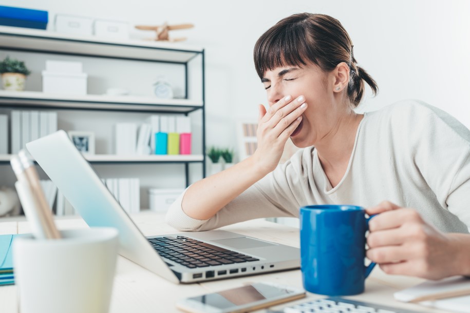 uma mulher sentada em uma mesa com um laptop e uma caneca de café