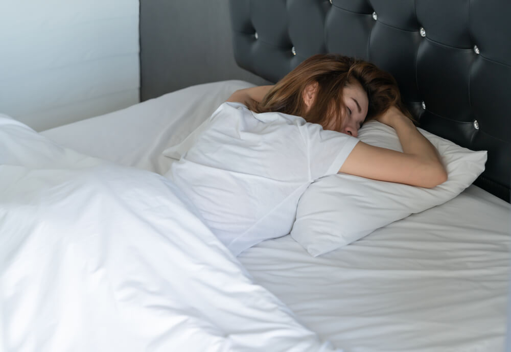 Imagem de uma mulher dormindo de bruços.