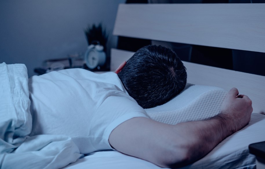 um homem deitado na cama com a cabeça apoiada no travesseiro