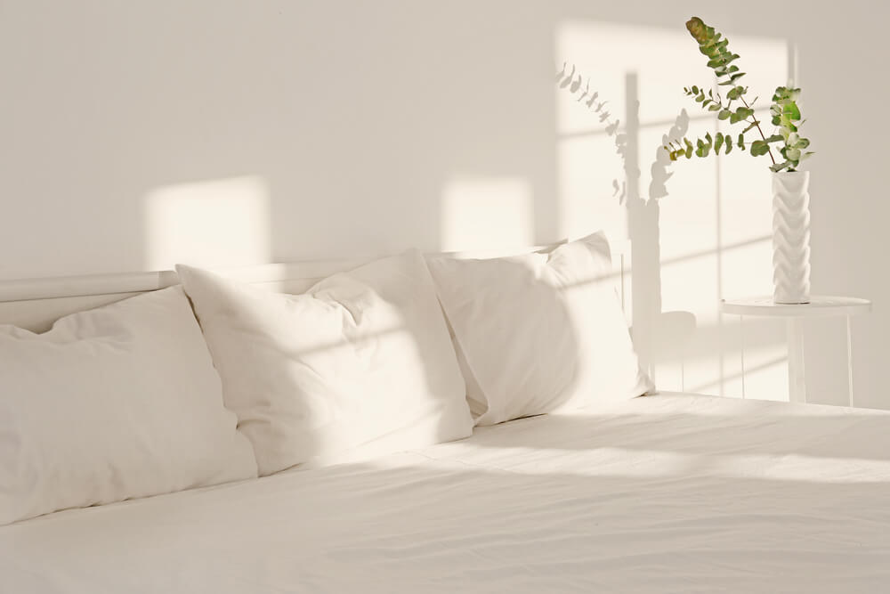 Imagem de uma cama recebendo iluminação indireta do sol.