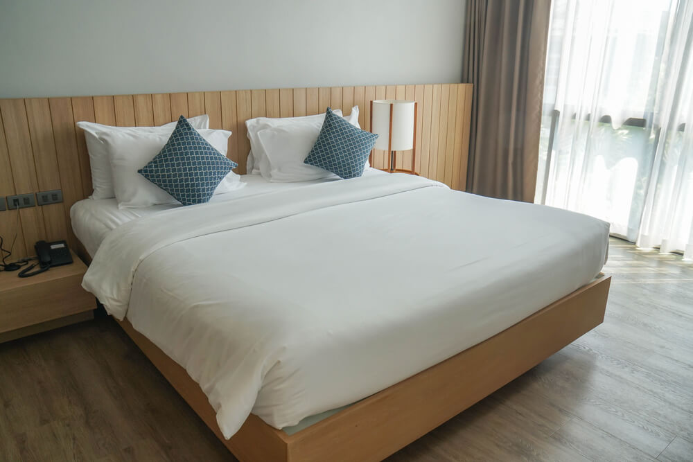 uma cama com lençóis brancos e travesseiros azuis