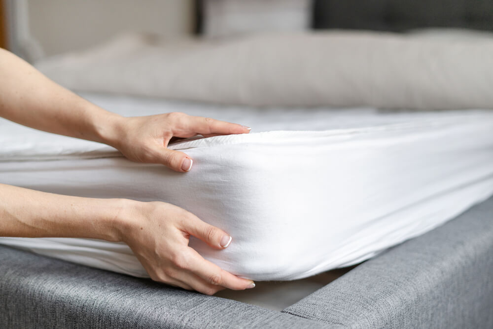 as mãos de uma mulher em uma cama com um lençol branco
