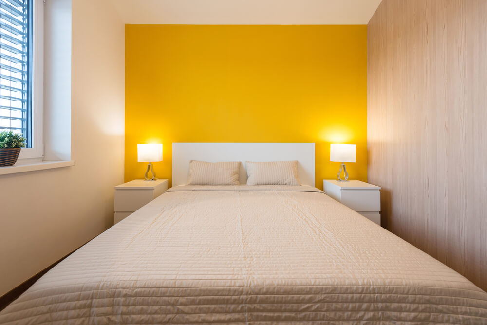 um quarto com paredes amarelas e uma cama branca