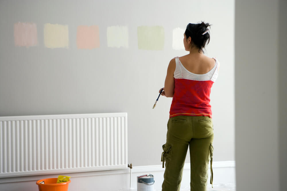 uma mulher pintando uma parede com um rolo de pintura