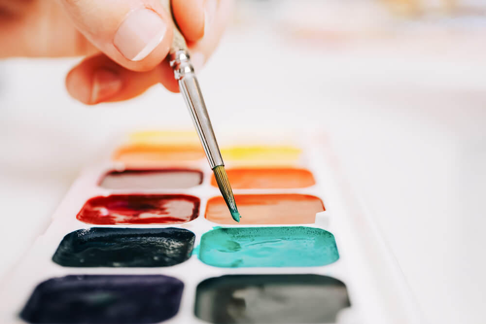 uma pessoa está segurando um pincel e pintando em uma paleta
