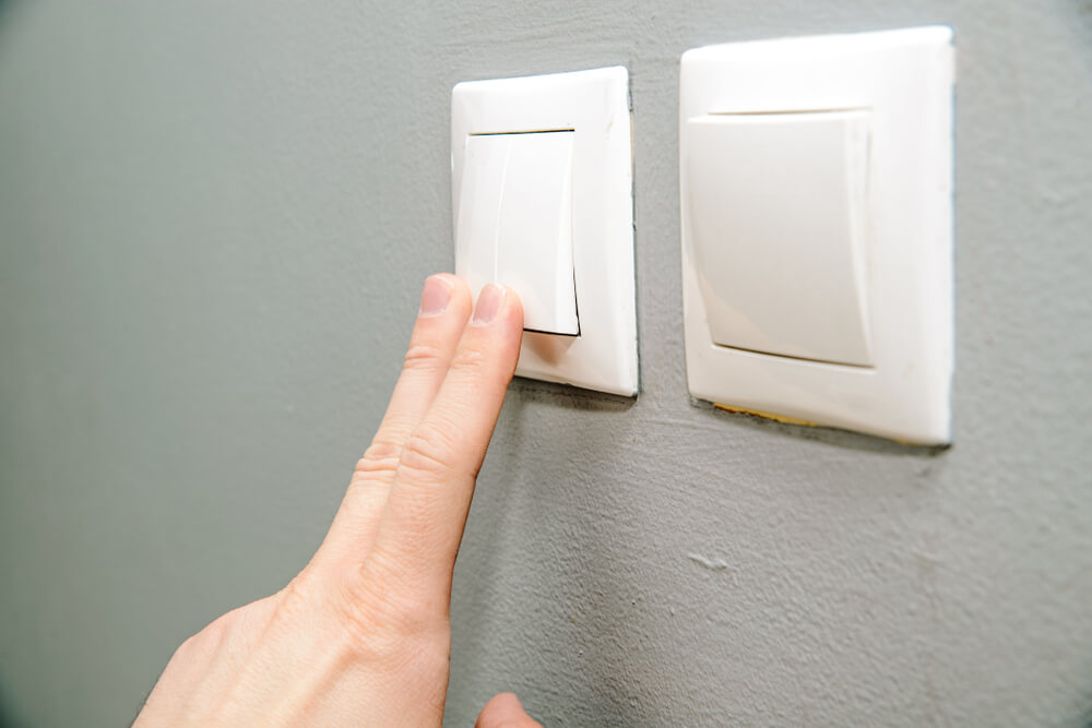 uma pessoa pressionando um interruptor de luz na parede