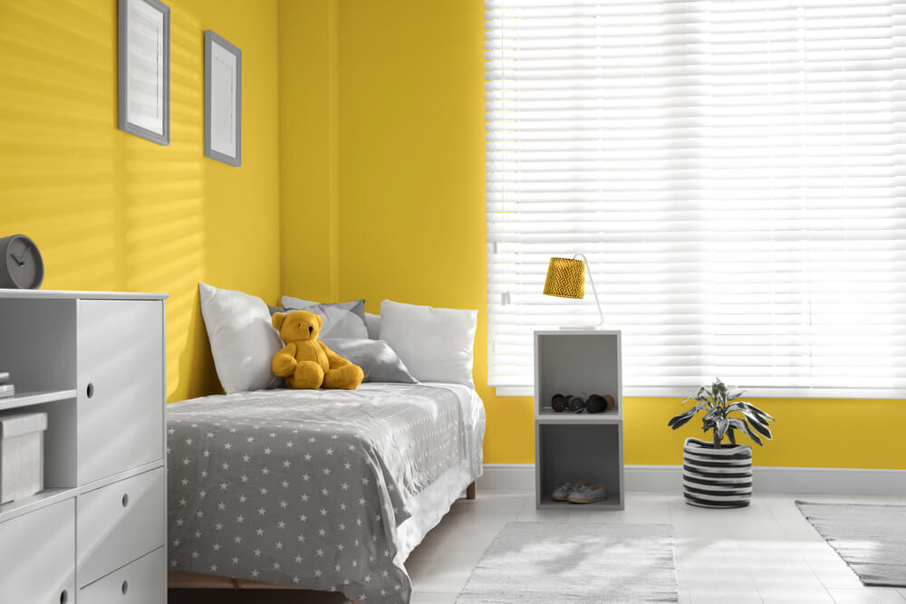 um quarto com paredes amarelas e móveis brancos