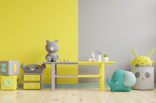 Imagem de da parede de um quarto de criança. Metade dela está pintada de cinza, enquanto a outra metade está pintada de amarelo.