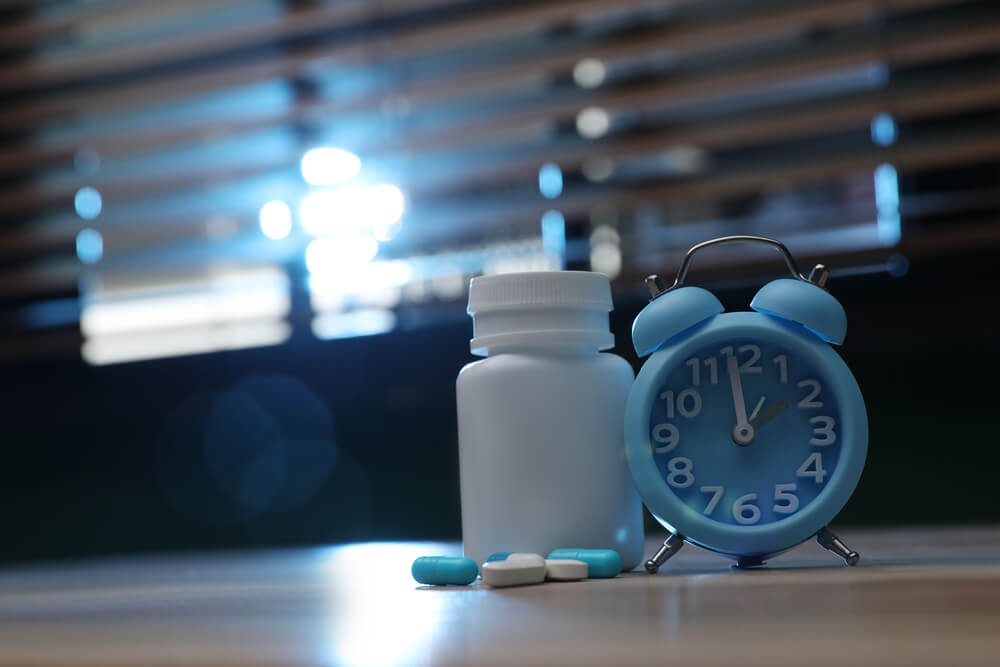 Imagem de remédios ao lado de um relógio.