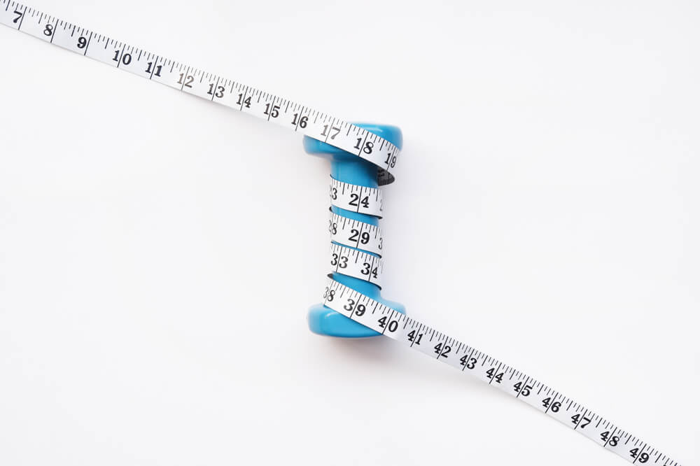 Imagem de uma fita métrica enrolada em um peso.