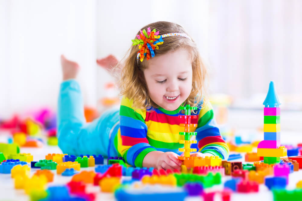 Imagem de uma criança brincando com legos no quarto.
