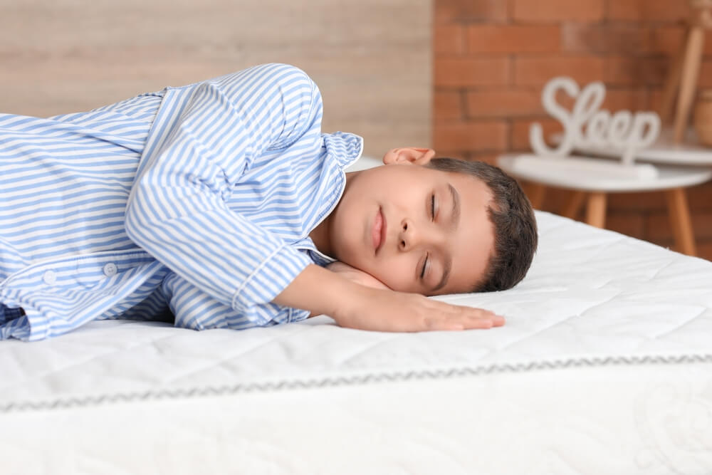 Imagem de uma criança deitada no melhor colchão de espuma dormindo.