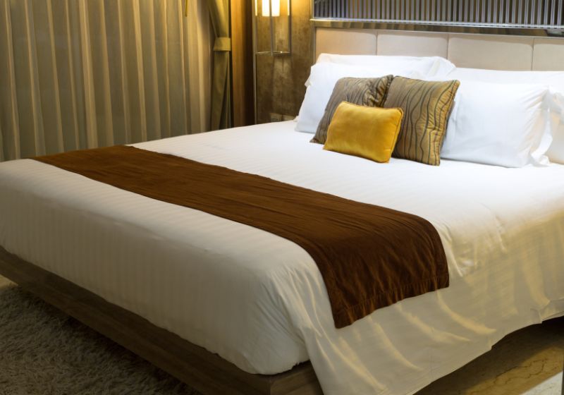 uma cama com cobertor e travesseiros marrons e brancos