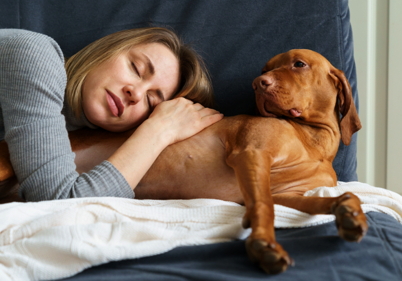 uma mulher deitada em um sofá com seu cachorro