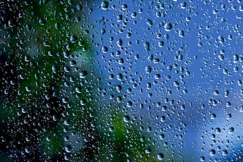 gotas de chuva em uma janela com um céu azul ao fundo