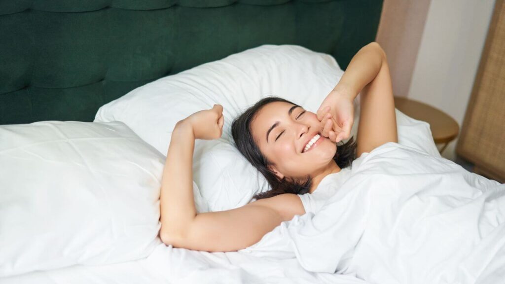 mulher sorridente acordando em sua cama pela manhã