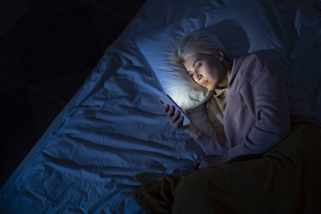 mulher deitada de noite mexendo no celular