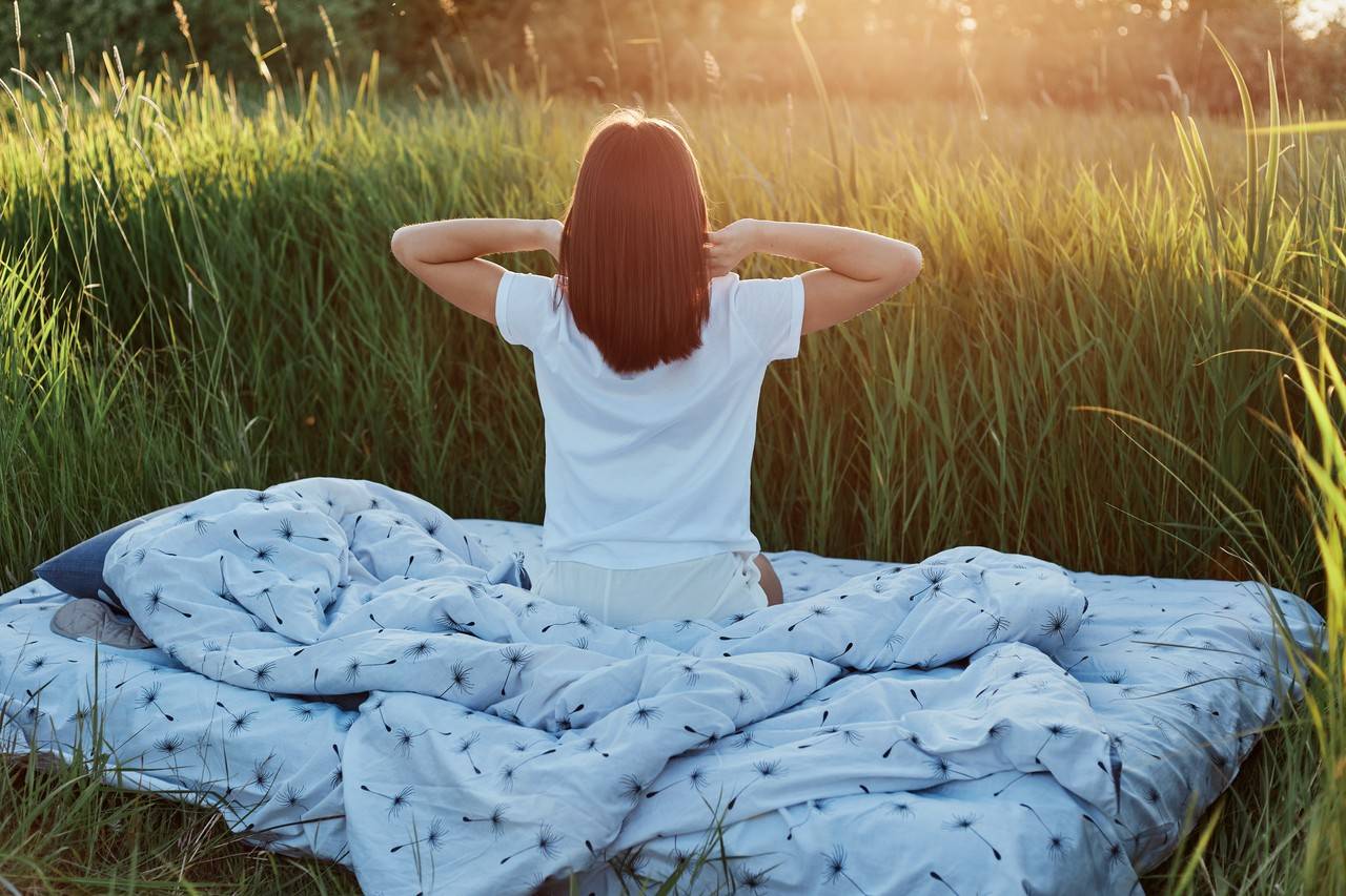 mulher sentada em um campo vendo nascer do sol